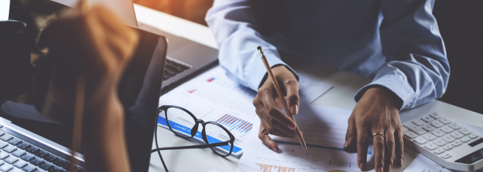 Person with pencil in their hand about to write on a financial report in a business setting