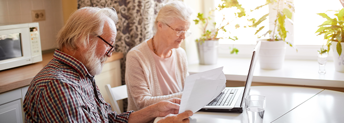 Seniors looking at paperwork and laptop together