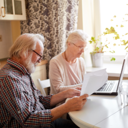 Seniors looking at paperwork and laptop together