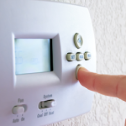 Finger about to press button on thermostat