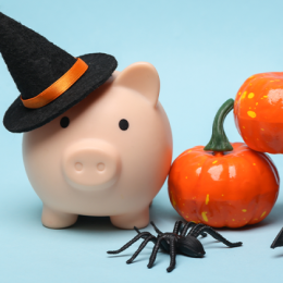 Piggy bank with a witch's hat, and orange ceramic pumpkins and a black bat next to it