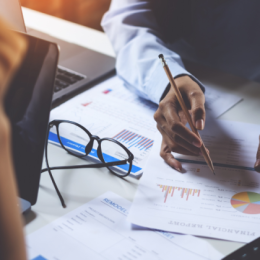 Person with pencil in their hand about to write on a financial report in a business setting