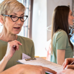 Older woman holding clipboard with man signing on it.